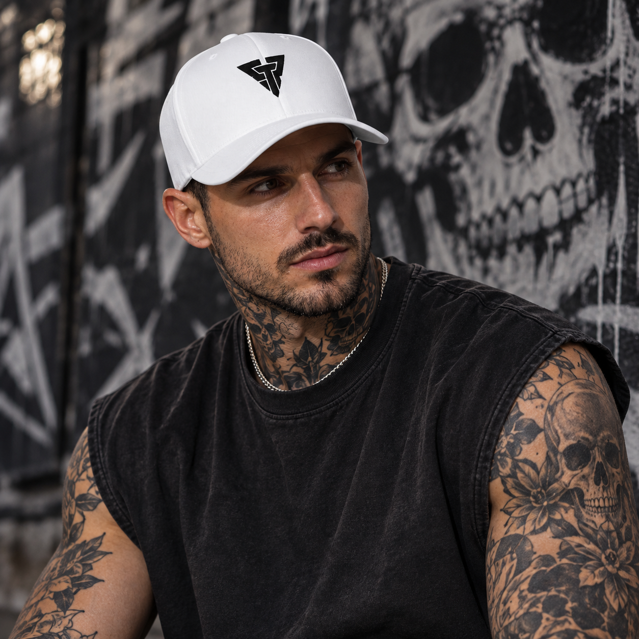 Man wearing the white CPT Onyx Cap in front of a graffiti skull wall